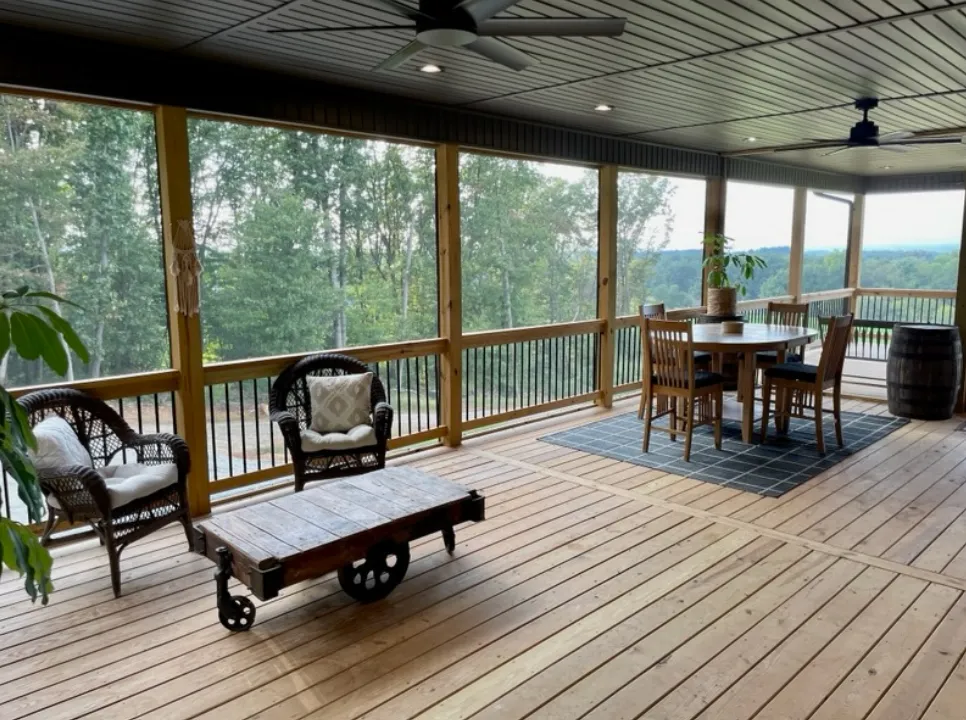 Screened porch with seating area, dining table, and panoramic windows overlooking mountain views - custom home construction